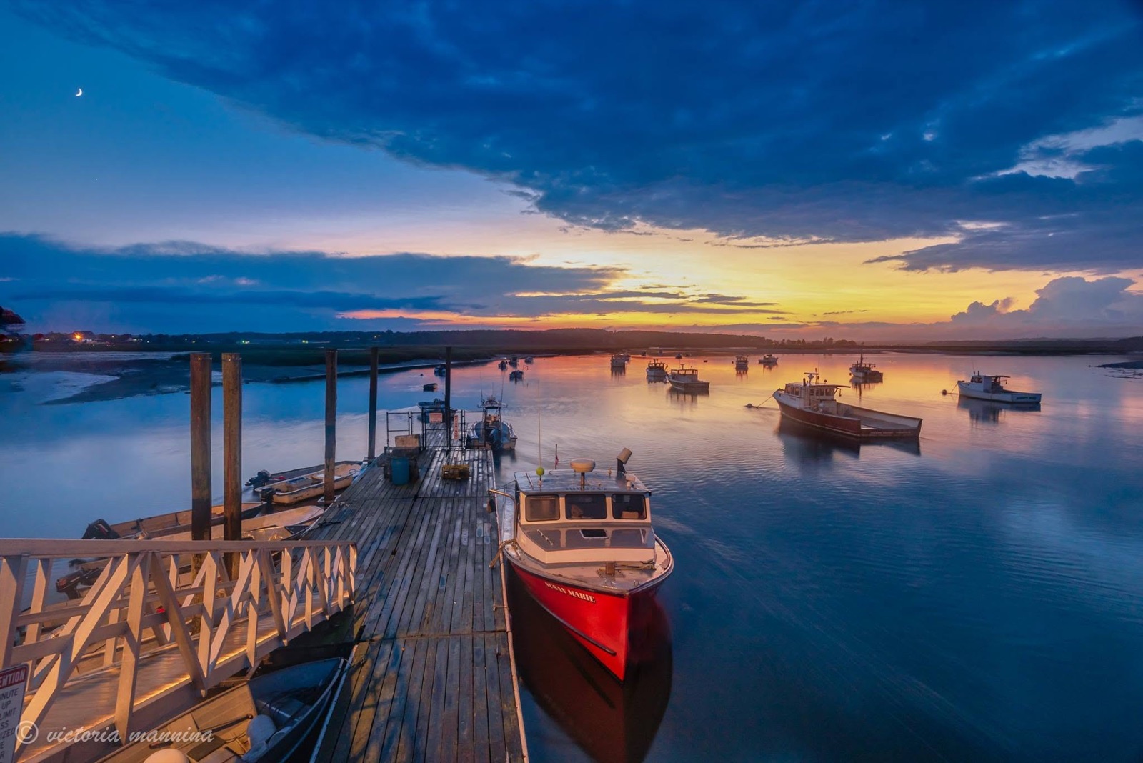 Fishing dock and moored boats under colorful sunrise sky