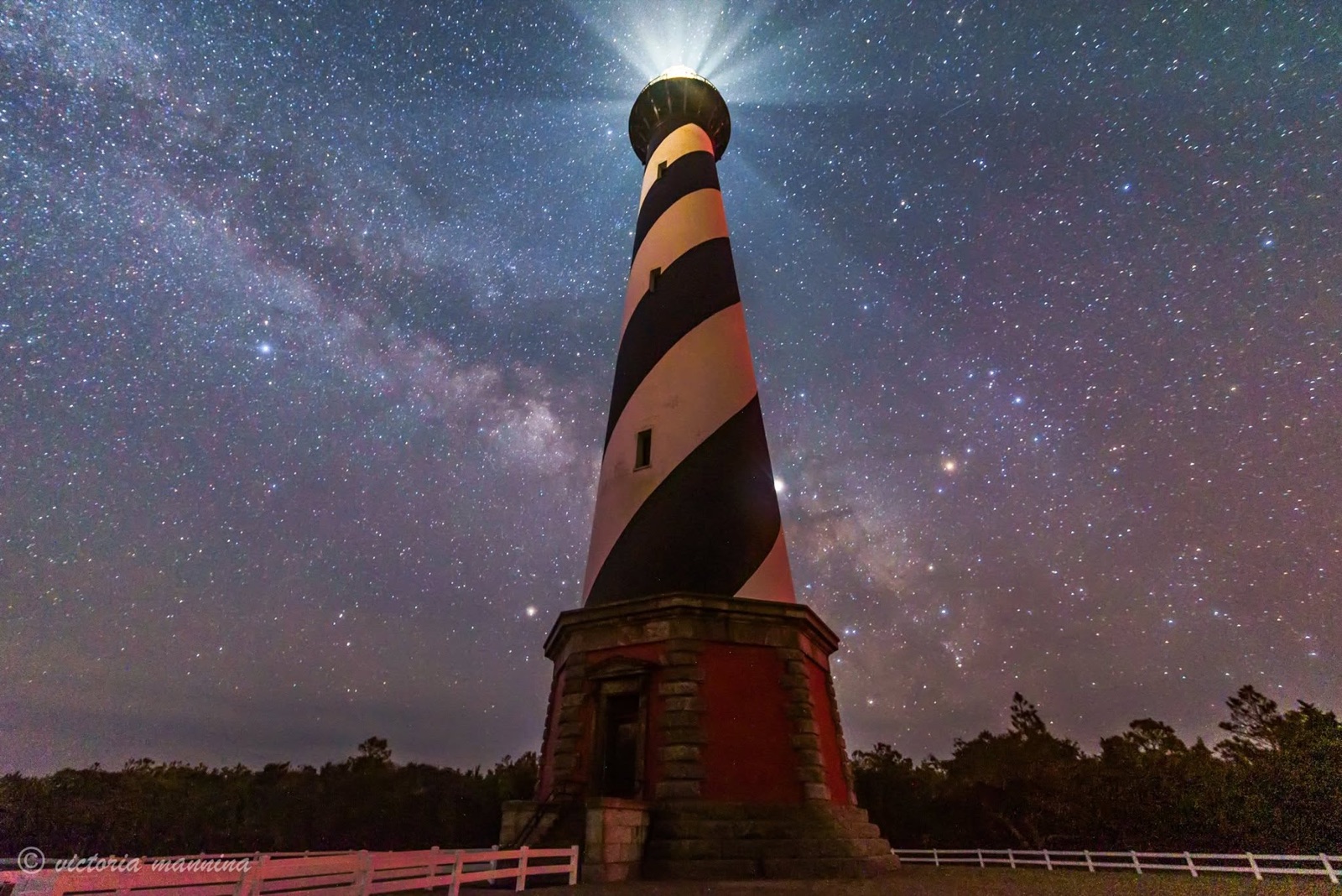 Lighthouse beacon radiating light rays under a starry sky