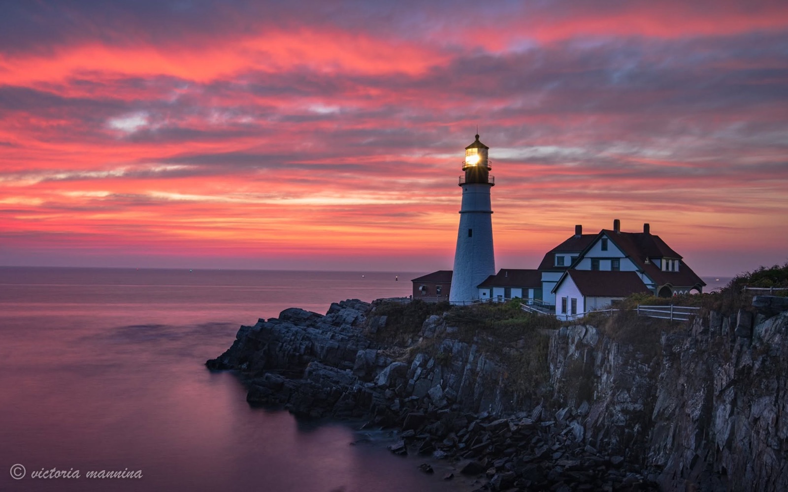 Lighthouse and house atop cliffs at sunset