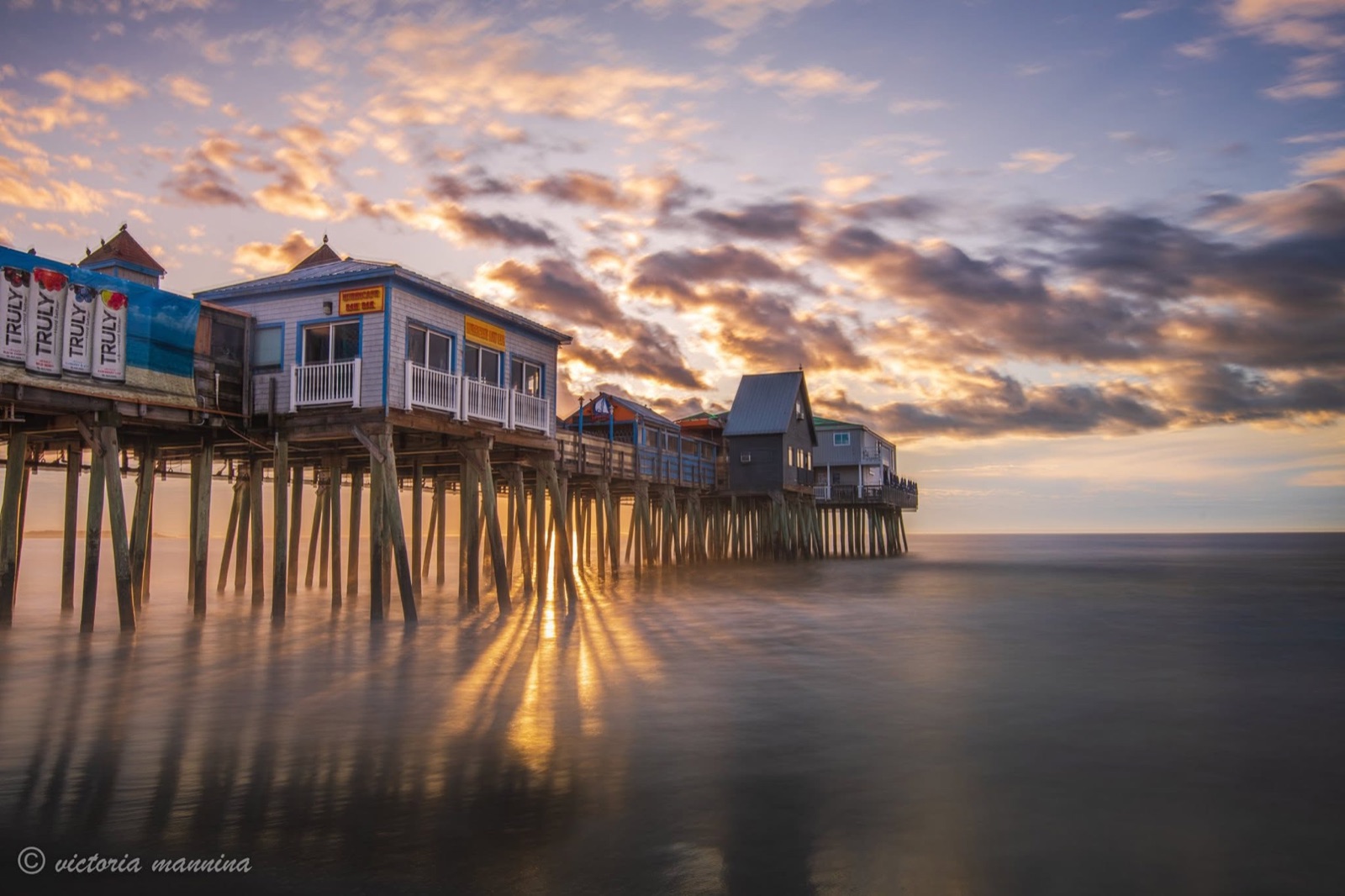 Wooden amusement pier over ocean at sunset